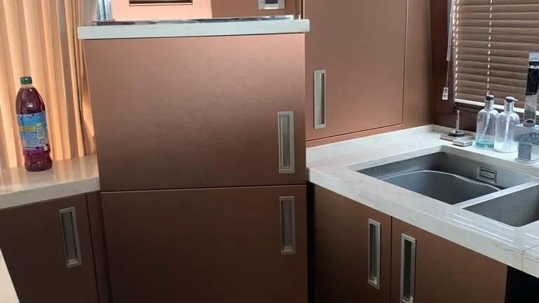 Modern kitchen featuring a brown fridge, sink, and cabinetry, with a large window and tiled flooring visible.